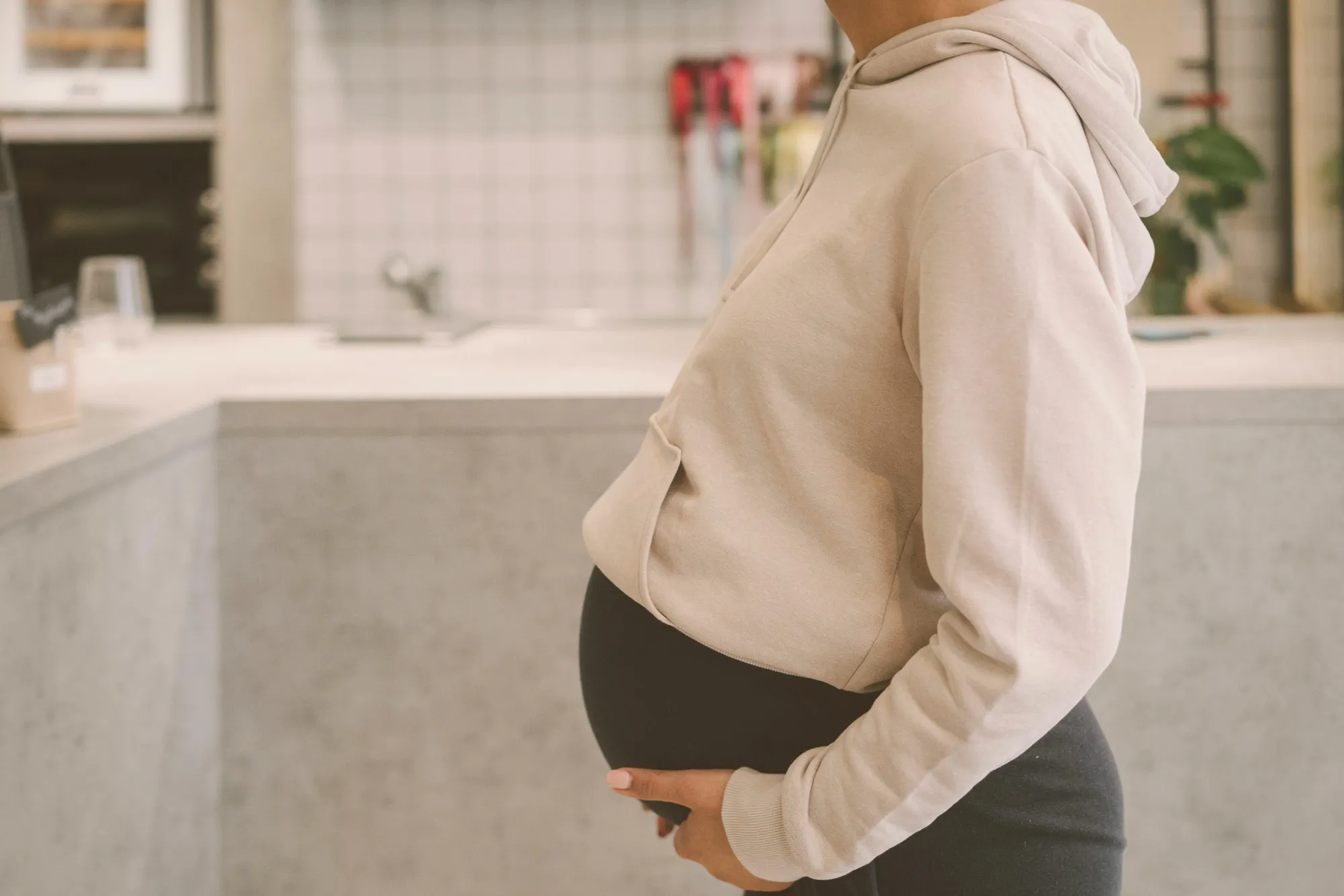 An expecting mother standing in her kitchen