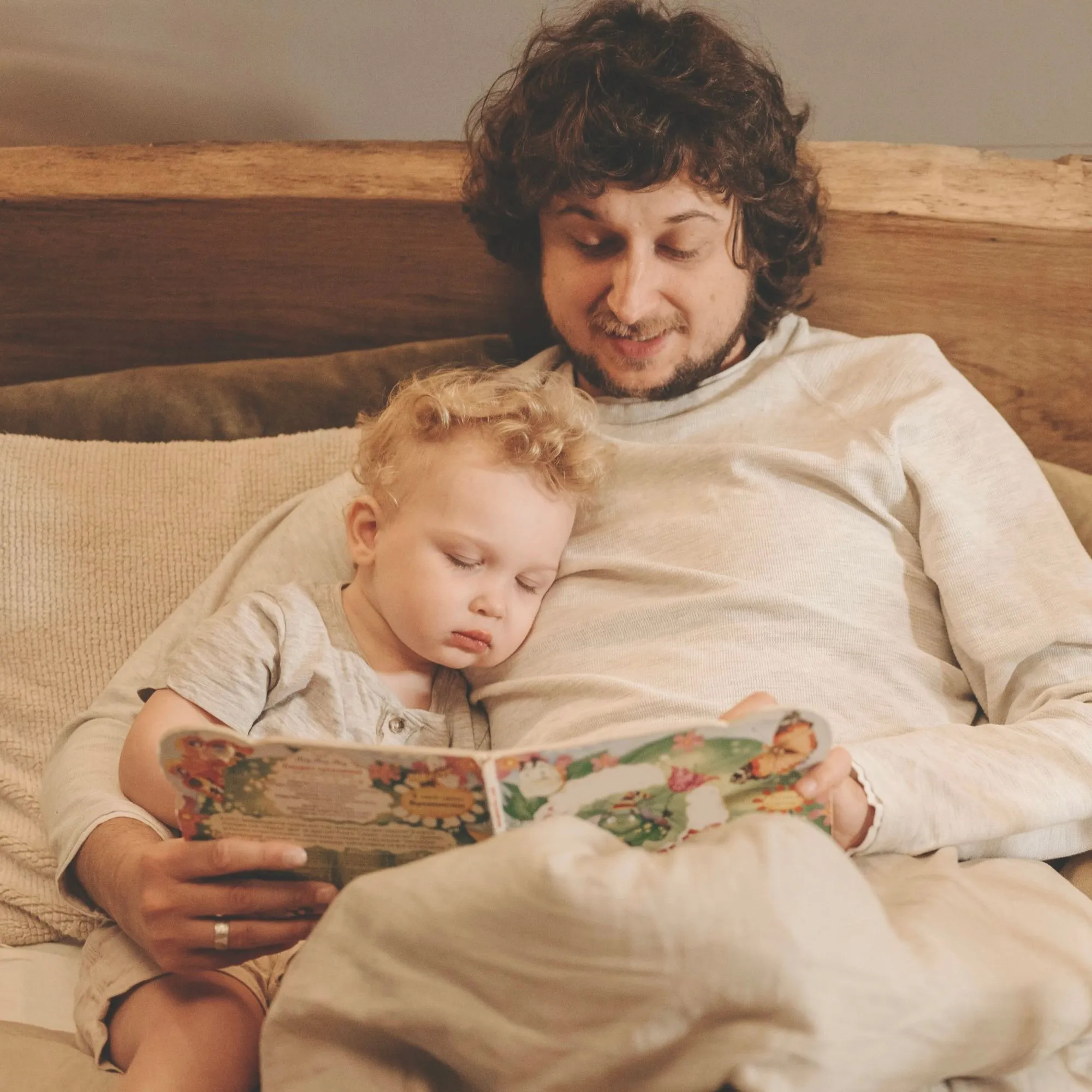 A father reading a picture book with his sleepy son